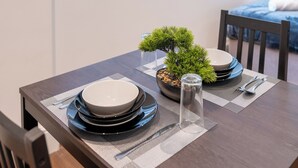A dining table set with plates, bowls, cutlery, and a bonsai tree.