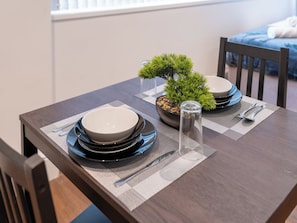 A dining table set with plates, bowls, cutlery, and a bonsai tree.