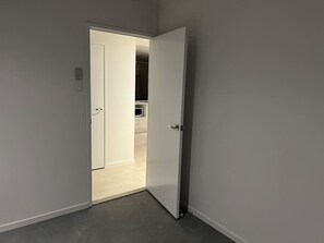 A hallway with a white door leading to a room with a tiled floor.