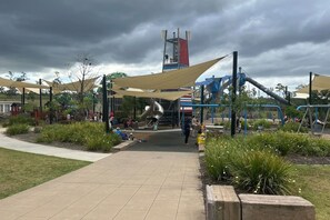 A playground with slides and swings, surrounded by shaded areas and greenery.