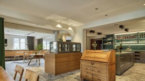 Un interior moderno con una barra de madera, una zona de estar con mesas y sillas, y una vitrina con botellas.