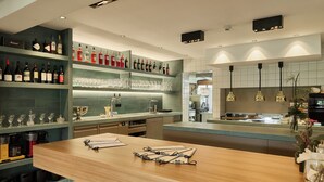 Cocina moderna con una isla de madera, zona de bar con botellas y vasos, y vistas al área de comedor.