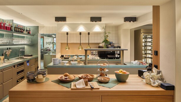 Una cocina moderna con una isla central, electrodomésticos integrados y una variedad de alimentos a la vista.