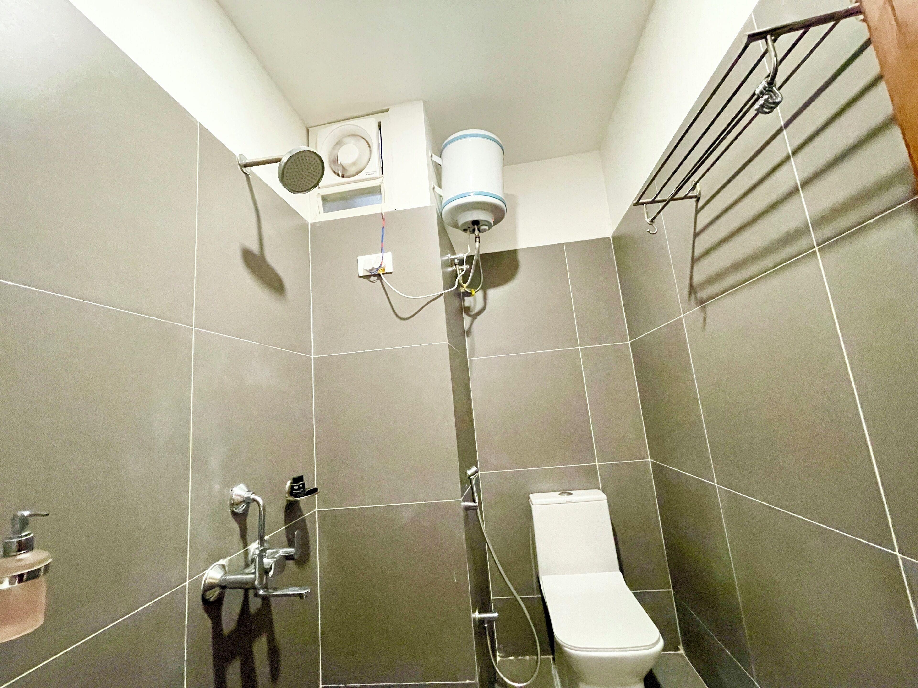 Un baño con inodoro, ducha y secador de manos.