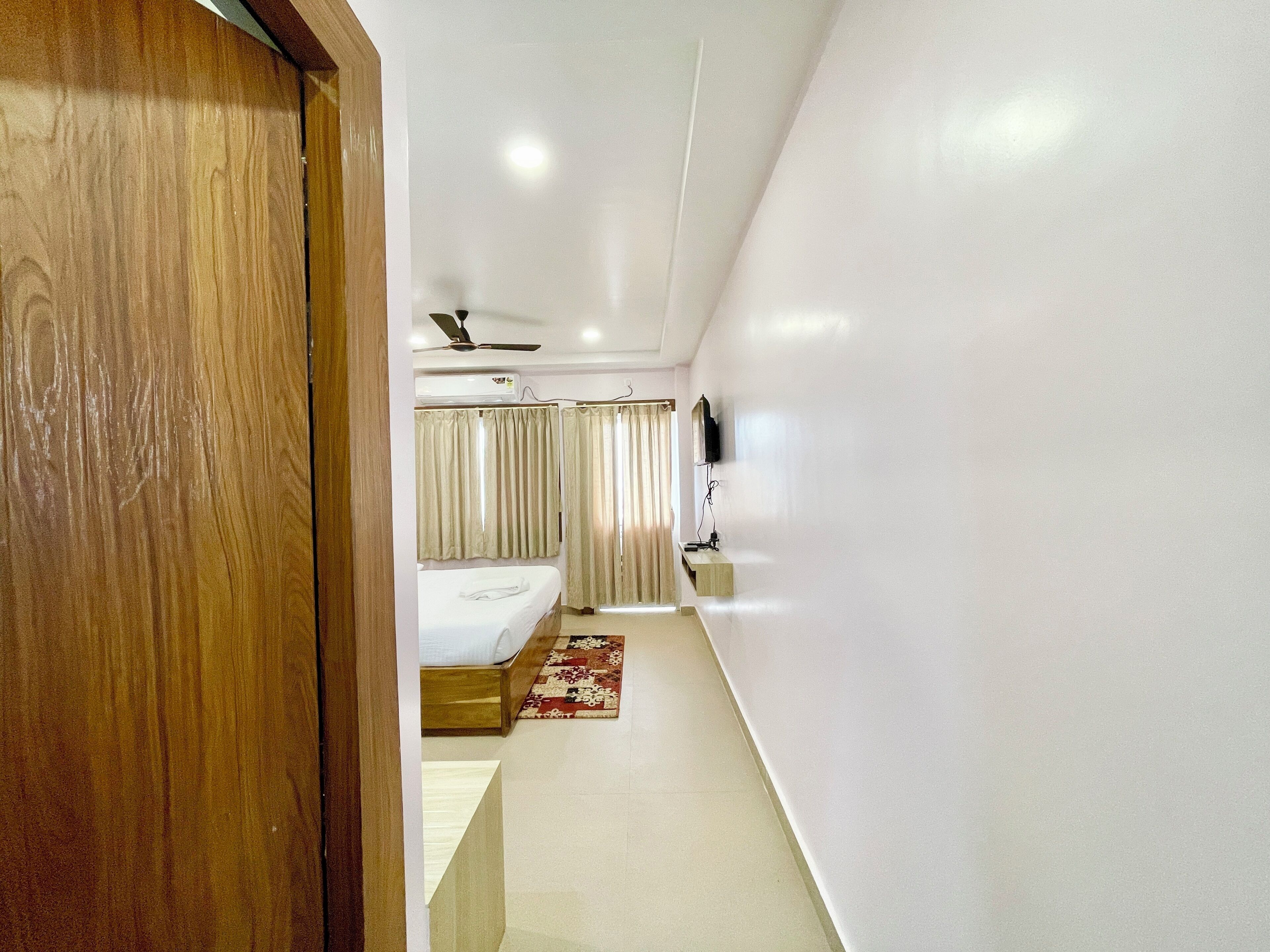Quarto de hotel com cama, televisão e ventoinha no teto.