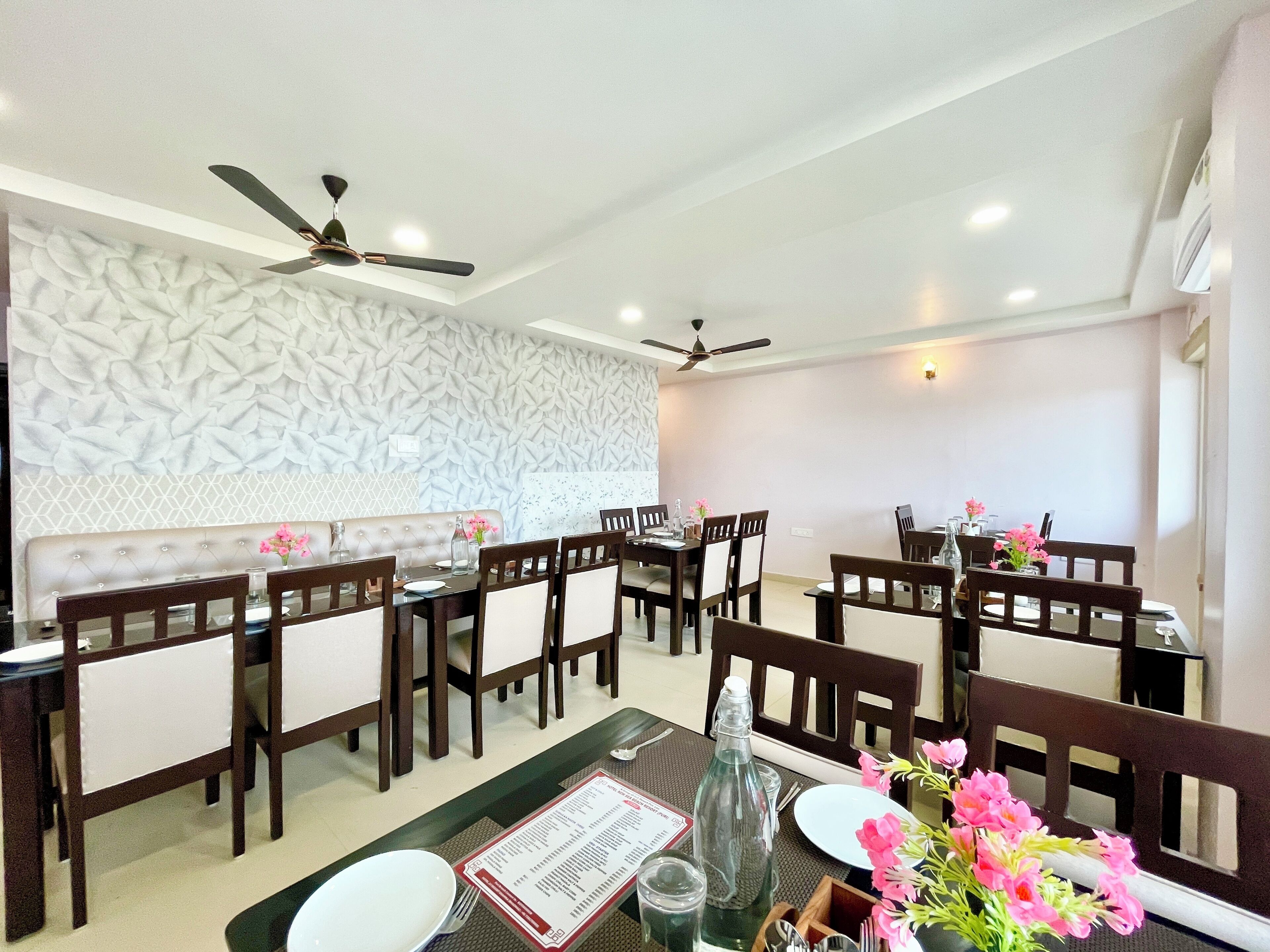 A dining area with multiple tables and chairs, ceiling fans, and decorative wall panels.