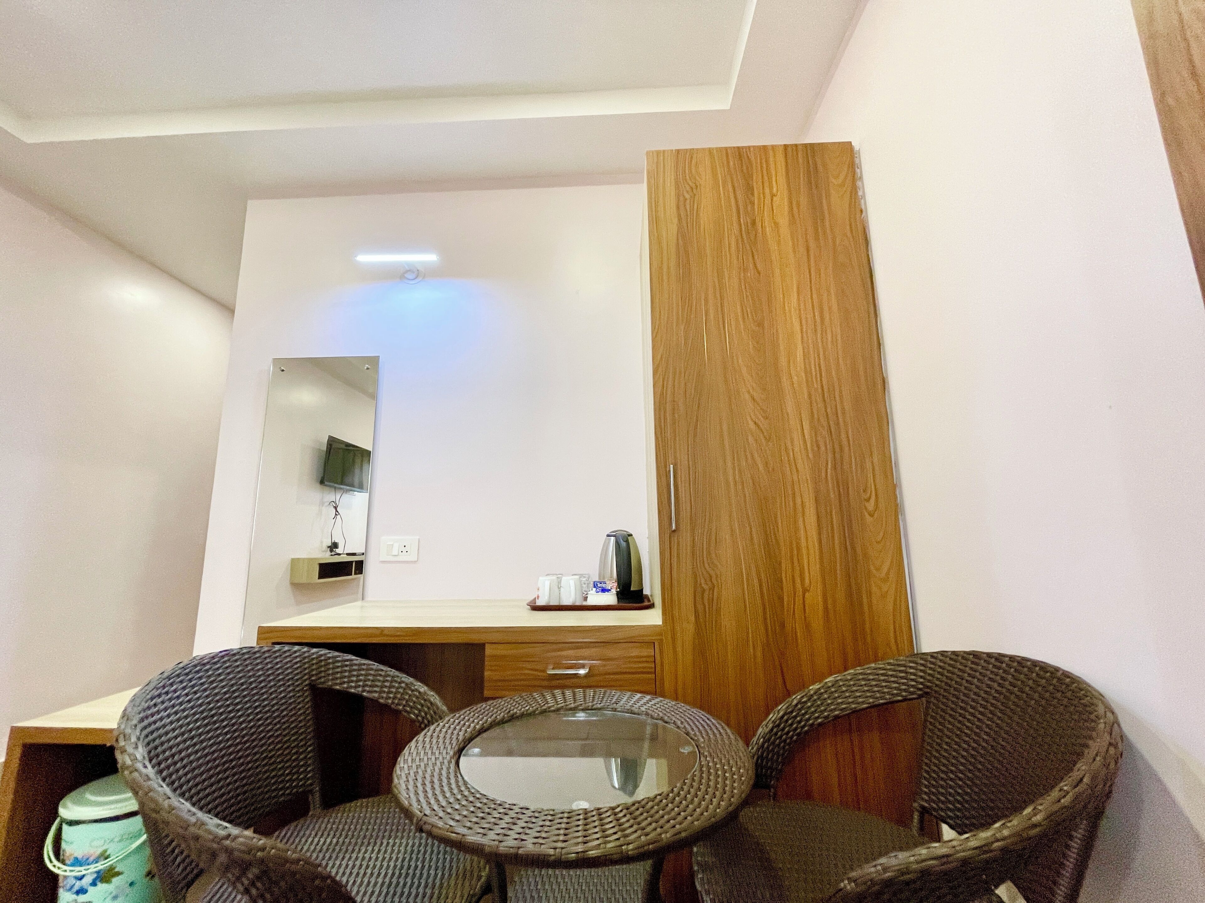 Una habitación moderna con una mesa de vidrio, sillas de mimbre, un armario de madera y un espejo.