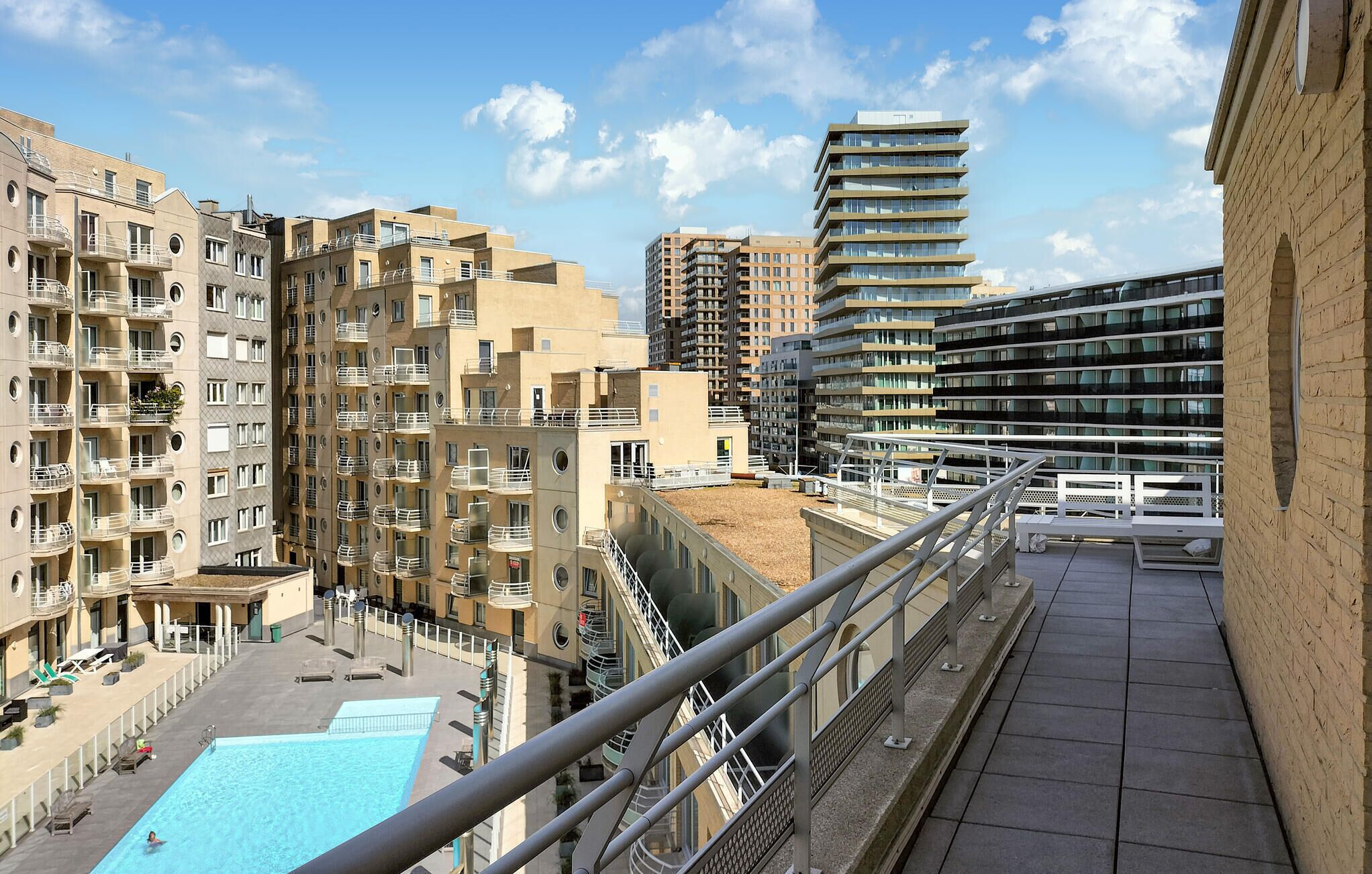 A high-rise building with multiple balconies and a rooftop pool area.