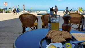 A table with a bottle of Blanche de Narmer, slices of bread, and butter on a beachside café table. - 2 bedroom lovely apartment in Oostende (Oostende)