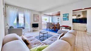 A living room with a sofa, TV, and dining area with chairs and a table.