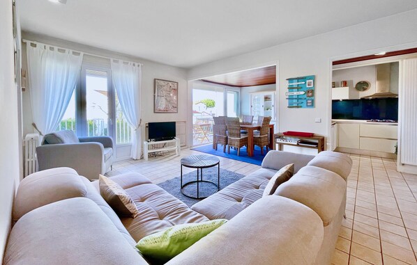 A living room with a sofa, TV, and dining area with chairs and a table.