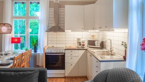 Una cocina compacta con armarios blancos, estufa, microondas y lavaplatos.