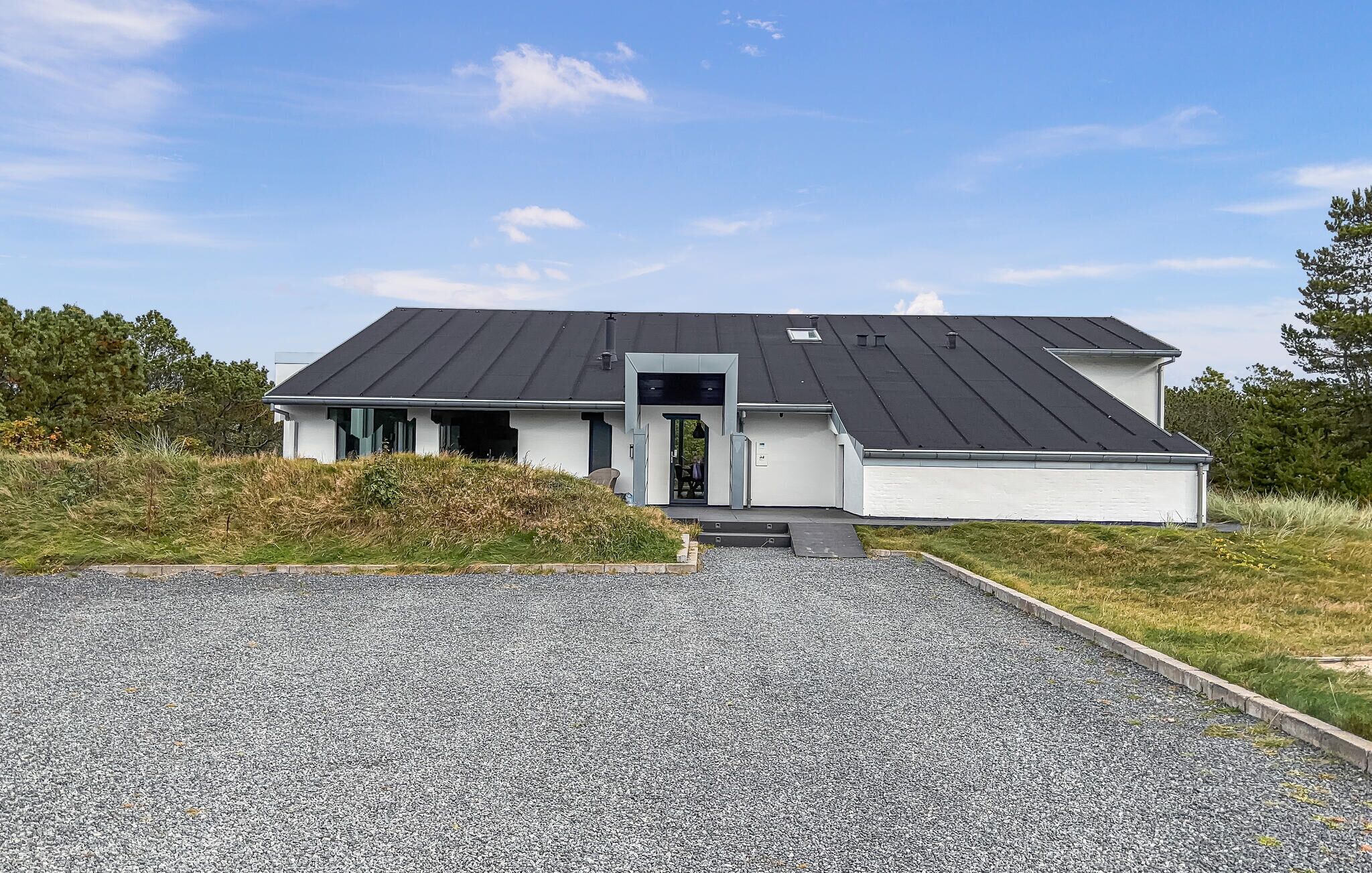 A modern two-story house with a dark roof, a front entrance, and a gravel driveway.