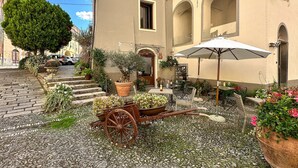 A cobblestone courtyard with a vintage cart, outdoor seating, and potted plants. - 1 bedroom stunning apartment in Pieve di Teco (Pieve di Teco)
