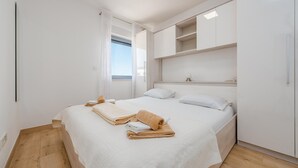 A bedroom with a bed, a window, and built-in storage cabinets.