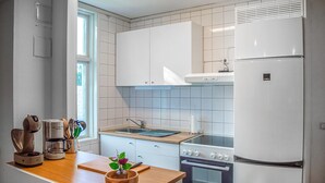 Een moderne keuken met witte kasten, een roestvrijstalen koelkast, een oven en een raam dat voor natuurlijk licht zorgt.