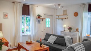 Een woonkamer met een bank, een houten salontafel, een lamp en een fles wijn.