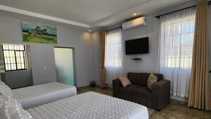 Una habitación de hotel con una cama grande, un sofá, un televisor y un cuadro en la pared.