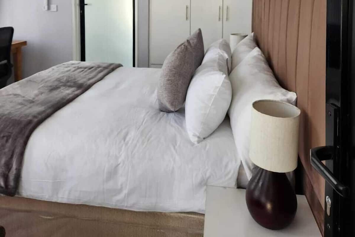 Habitación de hotel con cama, escritorio, silla, armario y un cuadro en la pared.