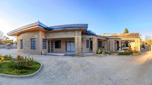 Una casa moderna con fachada de piedra, ventanas amplias y entrada con pavimento.