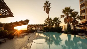 An outdoor swimming pool with a wooden deck, palm trees, and a pergola structure. - Elegant 1-bed Apartment With Premium Amenities (Melbourne)