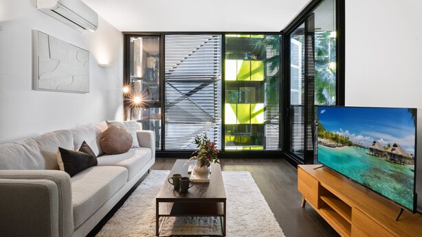 A modern living room with a sofa, coffee table, and TV. - Elegant 1-bed Apartment With Premium Amenities (Melbourne)