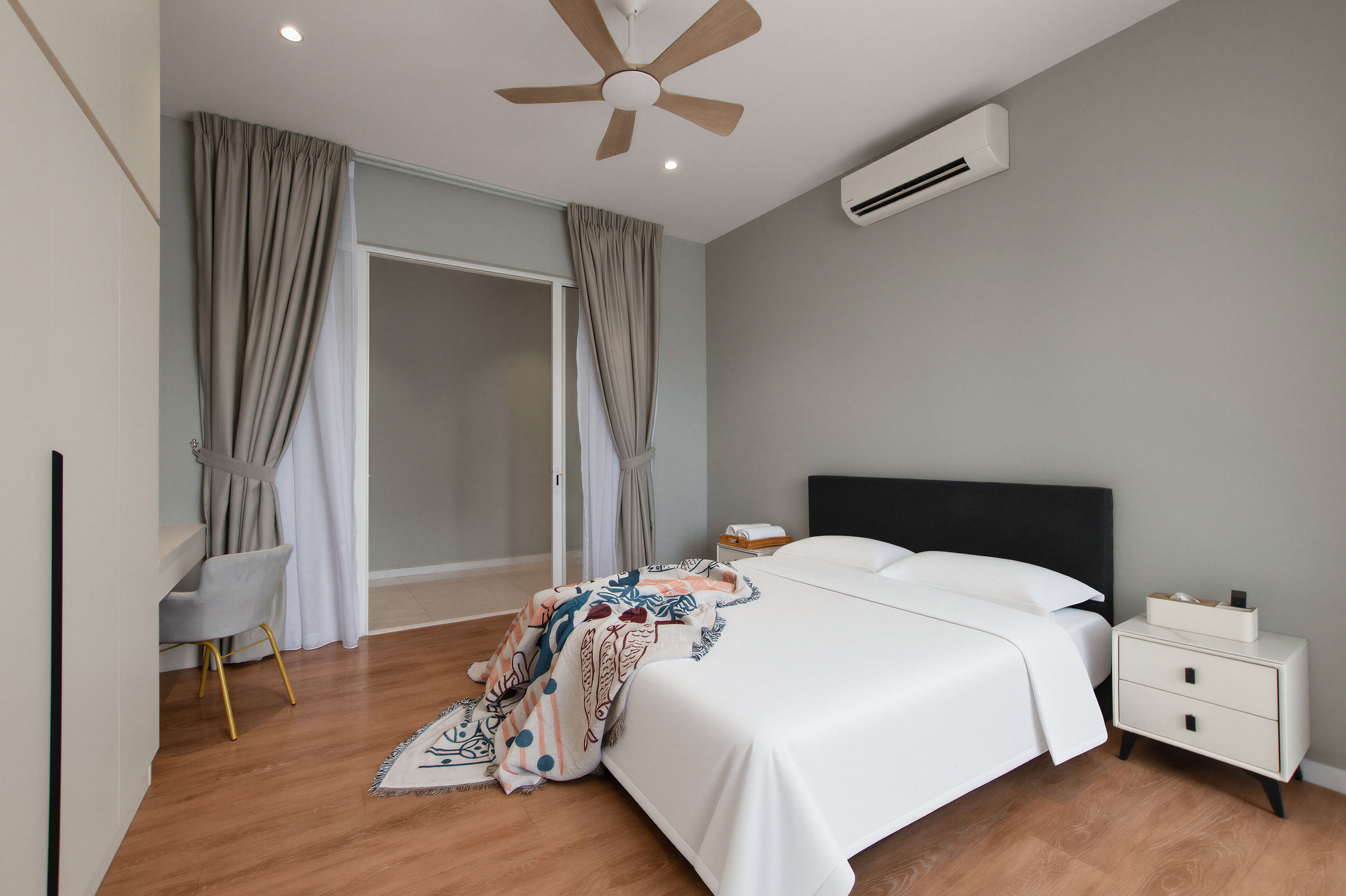 A bedroom with a bed, bedside table, nightstand, and a ceiling fan.