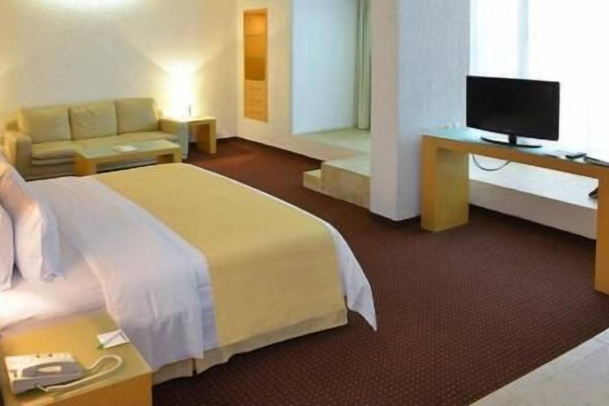 Une chambre d’hôtel comprenant un lit, un bureau avec une télévision, une lampe et un téléphone.