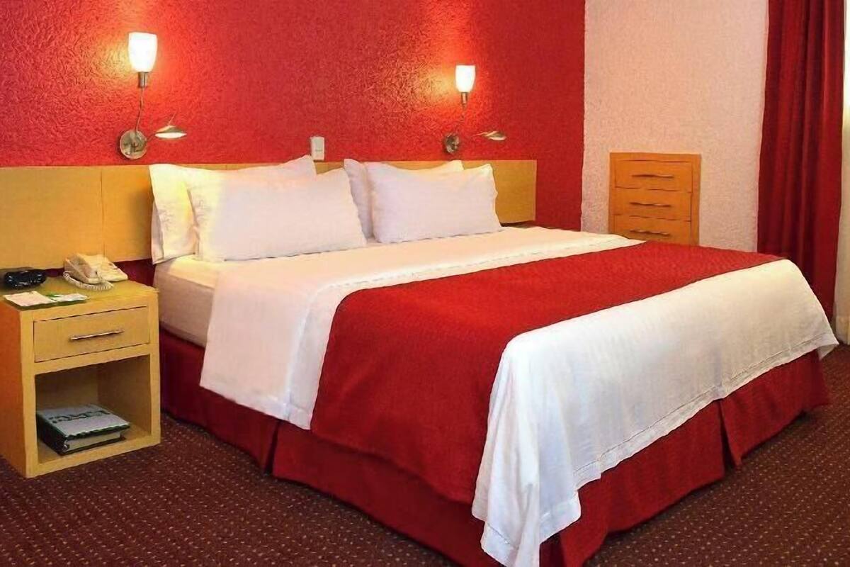 Une chambre d’hôtel comprenant un lit, des tables de chevet, une lampe, un téléphone et un tiroir.