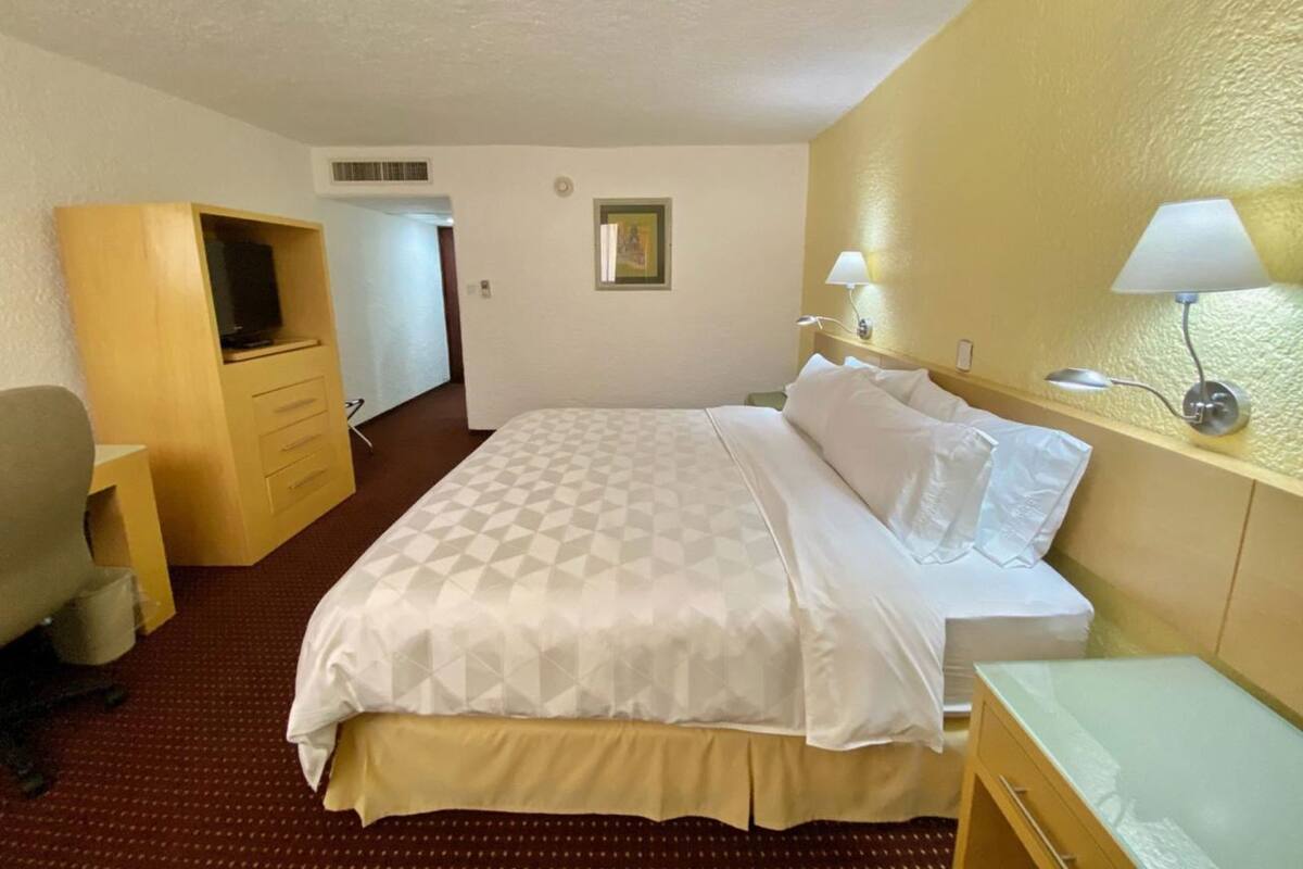 Une chambre d’hôtel équipée d’un lit, d’un bureau, d’une chaise, d’une télévision et d’une lampe.
