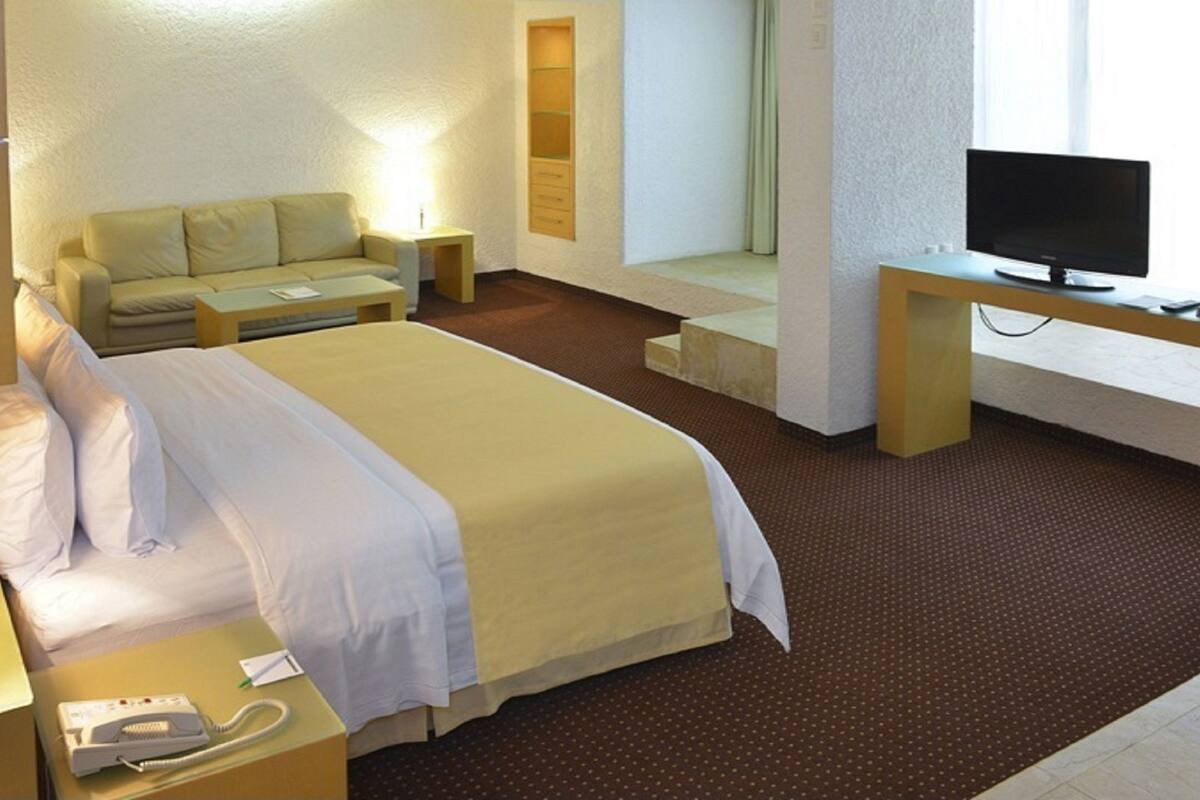 Une chambre d’hôtel comprenant un lit, un bureau avec une télévision, une lampe de chevet et un téléphone.