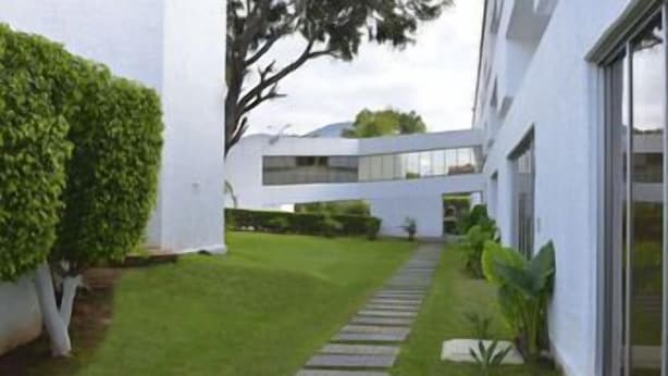 Een modern gebouw met een witte gevel, een geplaveid pad en een verzorgd gazon.