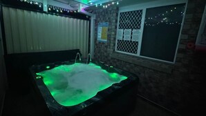 Una vasca idromassaggio con illuminazione verde, una finestra vista e un segnale di sicurezza della piscina.