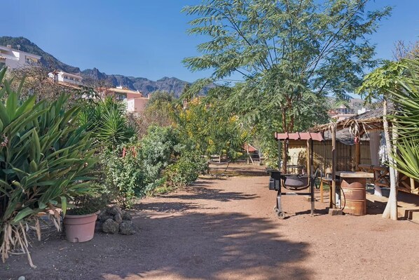 Un jardín con plantas en macetas, una estructura de madera y un sendero de tierra.