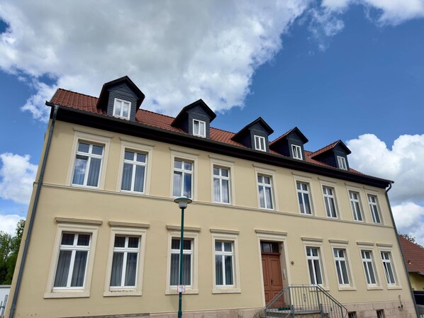 Un edificio a più piani con facciata simmetrica, numerose finestre e un ingresso centrale con una porta.