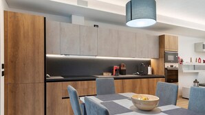 A modern kitchen with wooden cabinets, a black countertop, and a dining area with a table and chairs.