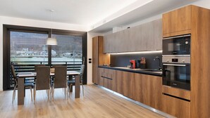 A modern kitchen with wooden cabinets, a built-in oven, and a dining area with a view.