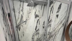 Un baño moderno con cabina de ducha de vidrio, un lavabo blanco y un salpicadero de mármol.