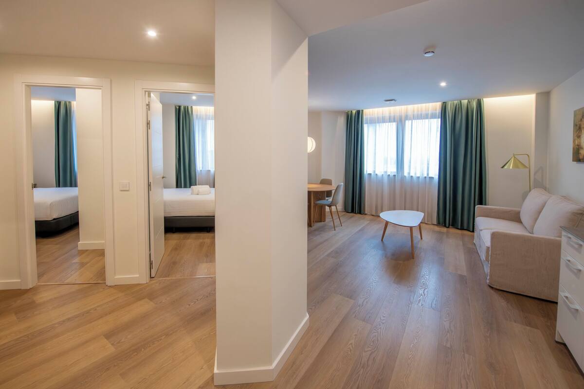 Une chambre d’hôtel moderne avec un plancher en bois, un lit, un canapé, une table à manger et un bureau.