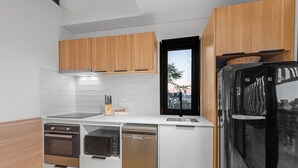 A modern kitchen with wooden cabinets, a built-in oven, microwave, and dishwasher. - Stylish New Farm Apartment With Courtyard (Brisbane)