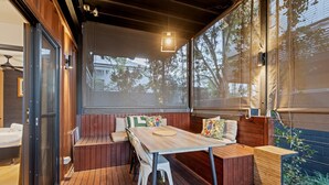 A wooden deck with a table and benches, a sliding glass door, and a view of trees and buildings. - Stylish New Farm Apartment With Courtyard (Brisbane)