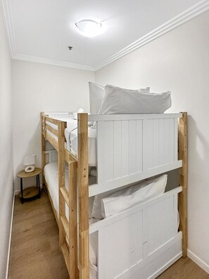 Un letto a castello con biancheria bianca e un comodino con una lampada.