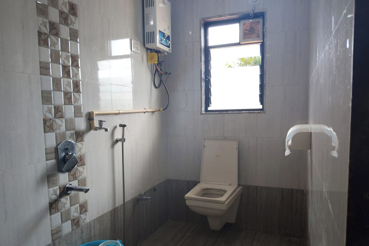 A small bathroom with a toilet, a shower, and a window.