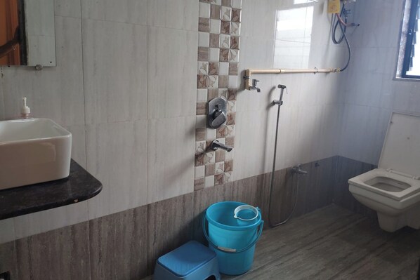 A bathroom with a sink, toilet, shower, and a blue bucket. - Mahabaleshwar Agro Village (Jaoli)