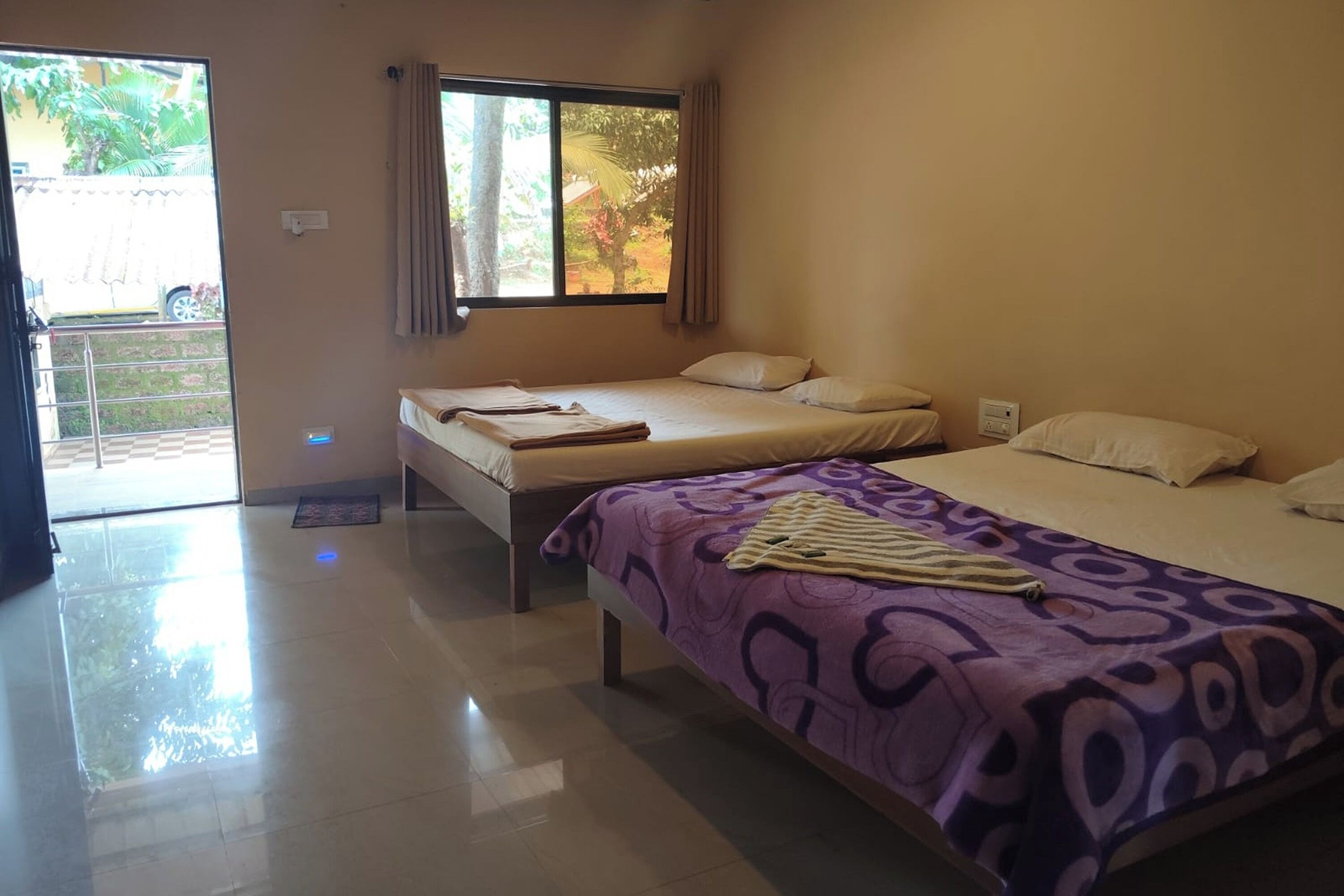 A hotel room with two beds, a large window, and a door leading to a balcony.