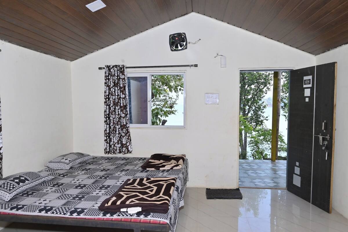 A bedroom with a bed, a window, and an open door leading outside.