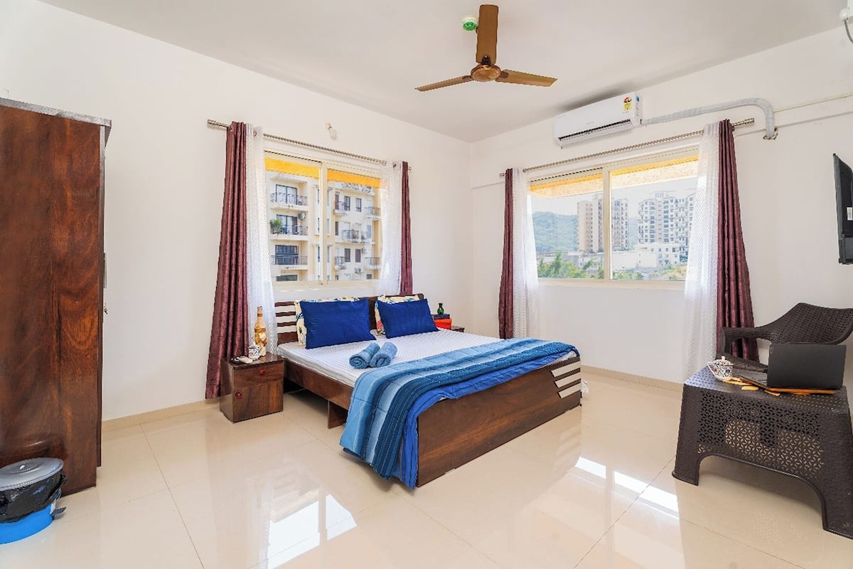 A bedroom with a bed, a desk, and a ceiling fan.