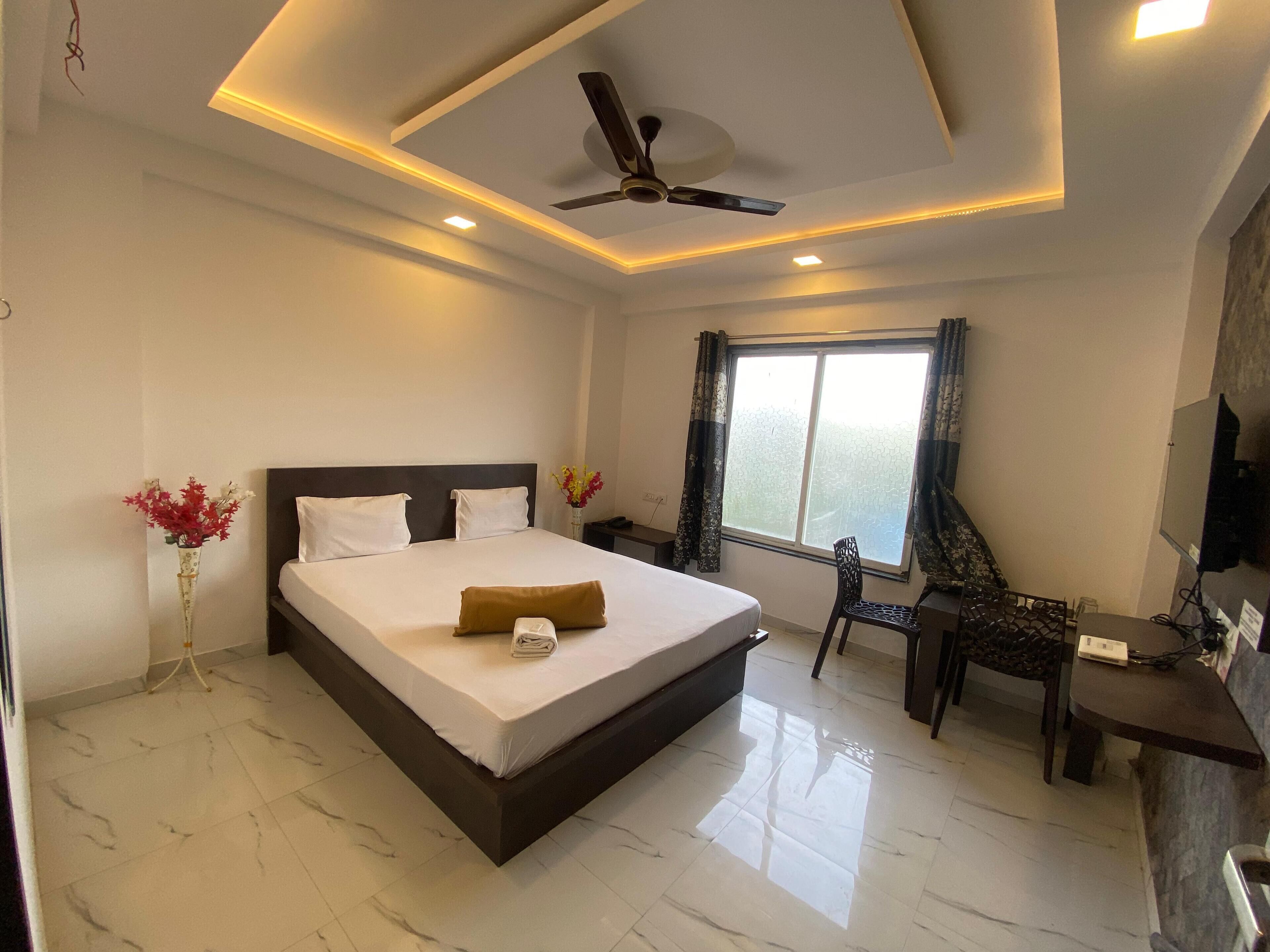 A modern hotel room with a large bed, a desk, and a ceiling fan.