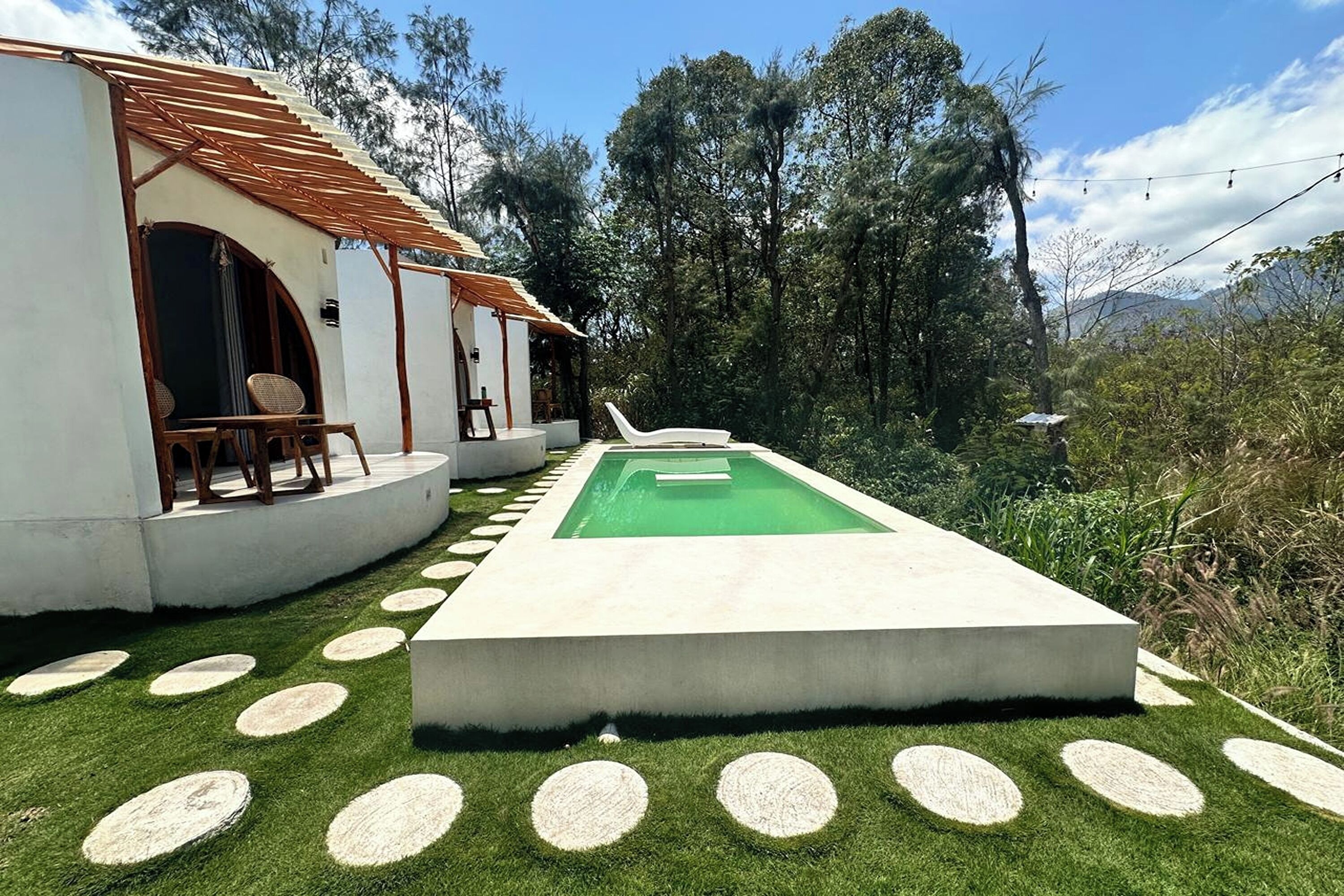 Una piscina con muelle de madera y un edificio blanco con porche cubierto.