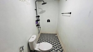 A small, compact bathroom with a toilet, a shower, and a tiled floor. - Felysia Villa III (Kintamani)